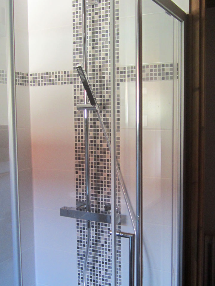Gros plans sur la colonne de douche et sa mosaïque